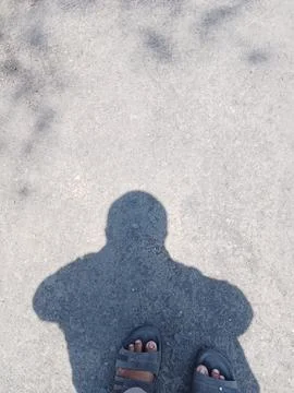 Shadow of a Man Standing on Asphalt Ground with Sandals POV Stock Photos