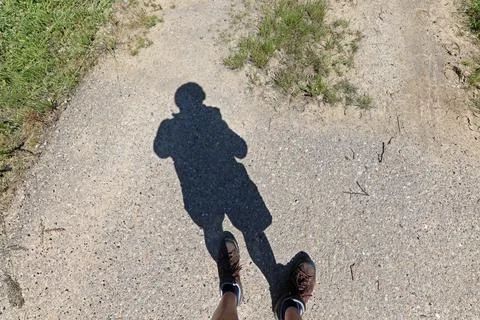 The shadow of a man standing on the pavement Stock Photos