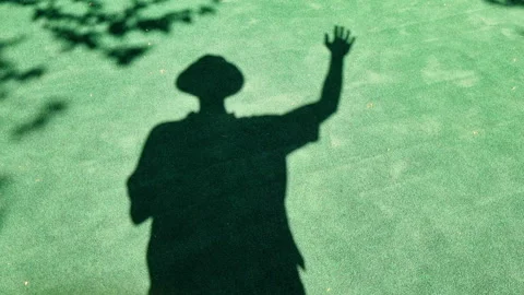 Shadow of a man who stands and waves his hand. Shadow on the pavement. Stock Footage 280772185