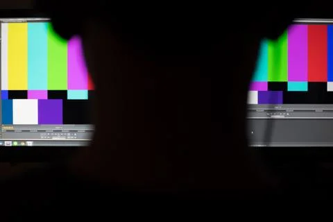 Shadow of man working in front of colorbars monitor workstation Foto stock
