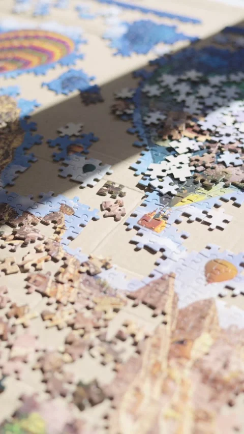 Shadow moving across a jigsaw puzzle of hot air balloons being assembled Stock Footage 332228945