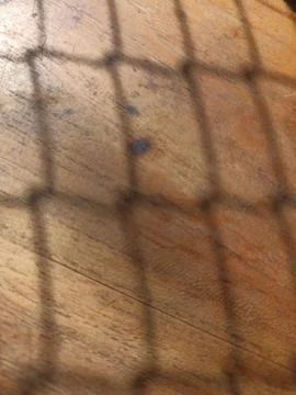 The shadow of a net on a wooden table can be used for an abstract background Stock Photos