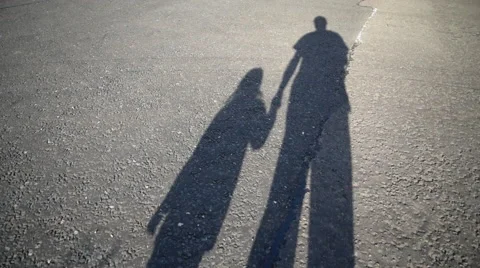Shadow of parent and child walking along road Stock Footage