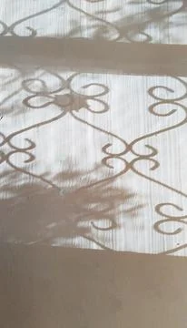 Shadow from patterned metal grille on light beige brown old wall. Mental Stock Photos