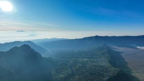 Shadow play across Tengger rumpled hills, where Bromo plume rises amid a Foto stock