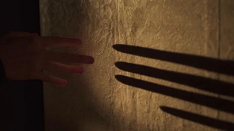 Shadow play. Black shadow of arm and fingers plays on the wall in orange light Video stock 100037517