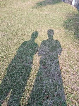 Shadow Play: Two Figures on the Grass Stock Photos