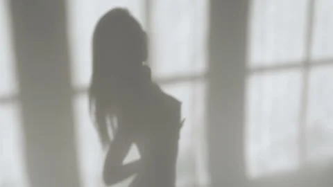 The shadow of the posing girl on the wall. Sexy girl posing against the white Video stock 101701358