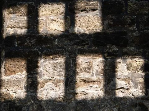 Shadow of prison bars on a stone wall Stock Photos