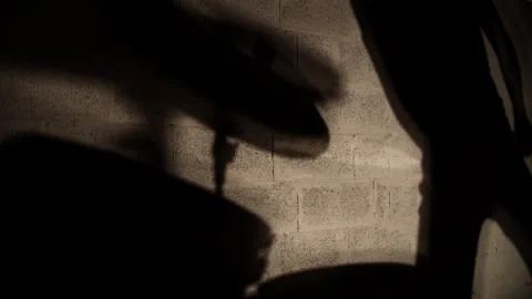 Shadow projected on wall of drummer sitting at drumkit and performing drum solo Stock Footage 345590889