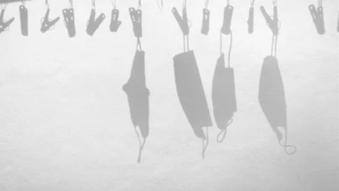 Shadow of protective masks hanging on clothesline in wind overlay on cement wall Stock Footage 152620433