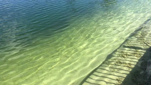Shadow of railing against clear pond water with small waves Stock Footage 132659787