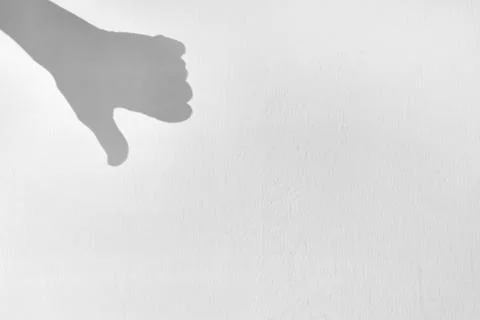 Shadow silhouette of hand with thumb down, on gray background, symbol Stock Photos