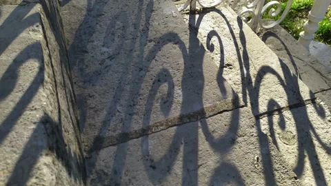 Shadow on stone stairs made of slabs cast by the curved pattern of wrought iron Stock Footage 233495103