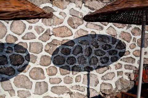 Shadow of straw beach umbrella on the stone wall at tourist resort. Beach umb Stock Photos