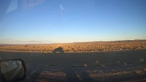 Shadow of a SUV from the side driving through a desert during a sunset Stock Footage 130644981