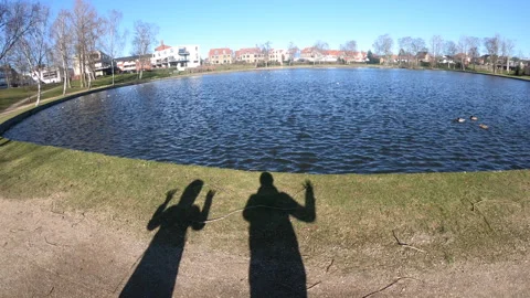 Shadow. Two human shadows are waving their hands near the lake. Stock Footage 269876464