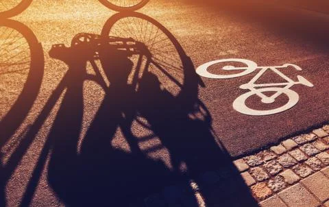 Shadow of unrecognizable cyclist on bicycle lane Stock Photos