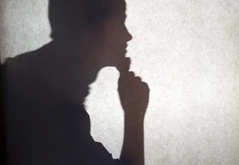 A shadow on the wall of a thinking guy. Stock Photos