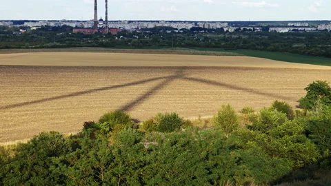 Shadow of wind turbine cast on field with industrial cityscape background Stock Footage 341130125