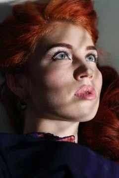 The shadow from the window falls on the face of a beautiful young woman wit.. Stock Photos