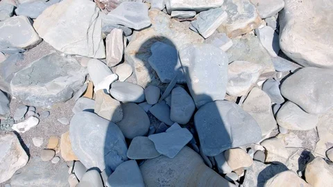 Shadow of woman with camera on stone pebble beach. Video stock 116178545