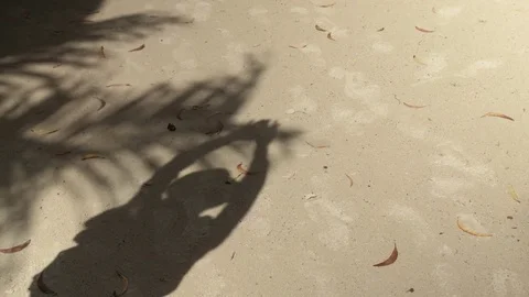 Shadow of a woman in hat reflected on the sand at the beach. 動画素材 83863452