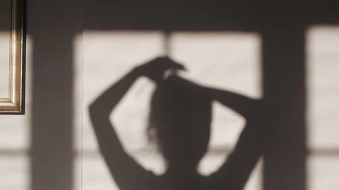 Shadow of woman making ponytail from her hair at home Stock Footage