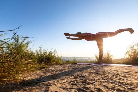 Shadow of a yoga master woman practicing yoga on the grass at sunrise Stock Photos