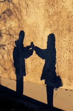 Shadow of young couple facing each other and holding hands Stock Photos