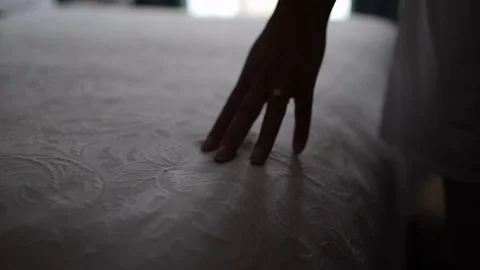 Shadowed hand rubbing across bed spread 動画素材 97815683