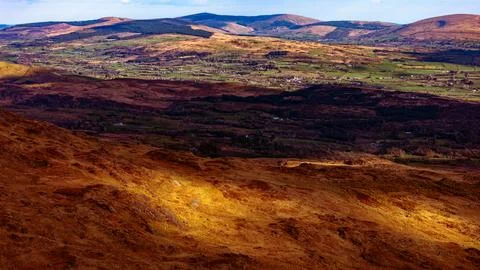 Shadows and sunlight fall over rolling hills and farmland Fotos Stock