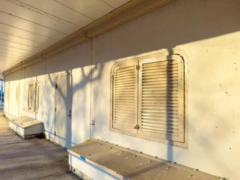 Shadows cast by trees on a wall with closed shutters in a sunny outdoor are.. 写真素材