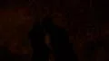 The shadows of a couple kissing is reflected on hay at night, lit up in orange HD Footage