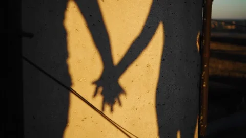 The shadows of the couple's hands are visible on the wall at sunset Stock Footage 305835170