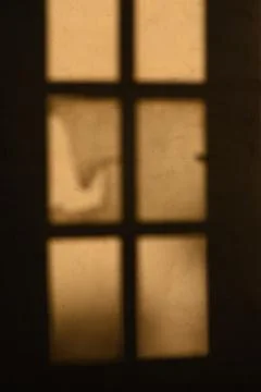 Shadows dancing through elegant windowpanes at dusk, hinting at stories unt.. Stock Photos