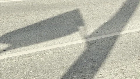 Shadows of a flag and pole stretch across an empty asphalt road Stock Footage 336937607