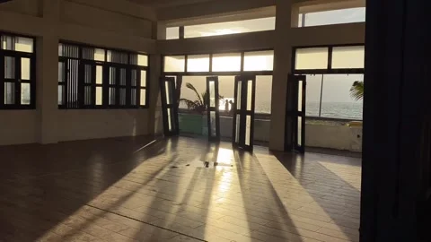 Shadows flood an empty seaside function hall at the beach during sunset. Video stock 260973542