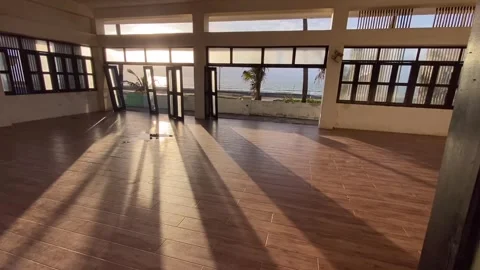 Shadows flood an empty seaside function hall at the beach during sunset. Video stock 260973561