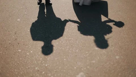 The shadows of lovers walking hand in hand are visible on the sidewalk Stock Footage 308870671