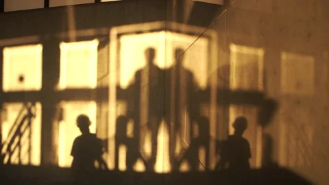Shadows of people on a marble wall walking into an underpass during sunset in Stock Footage 279837039