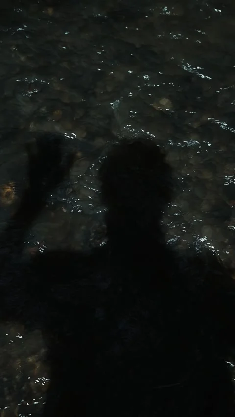Shadows of a person playfully interact with water, creating intriguing shapes on Stock Footage 344439932
