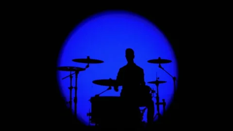 Shadows from smoke and a drummer beating the beat in a round ray of blue light Stock Footage 131201598