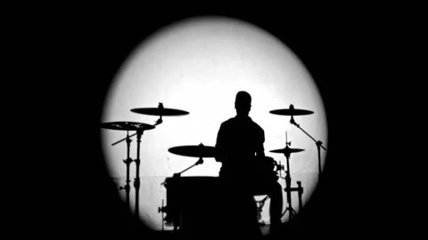 Shadows from smoke and a drummer beating the beat in a round ray of white light Stock Footage 131548331