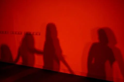 Shadows of three figures on a red wall creating abstract patterns Stock Photos