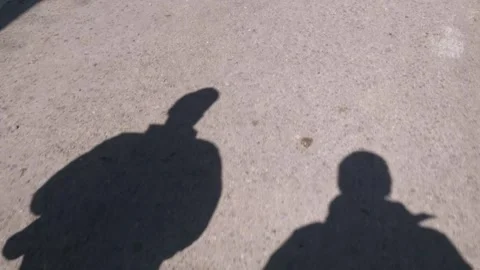 Shadows of two men taking a stroll on a sunny day Видео 267606700