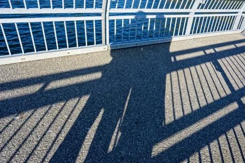 Shadows of two people embracing on concrete pier by sea Stock Photos