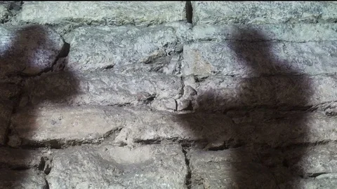 Shadows of two people talking projected on a stone wall Stock Footage 87196772
