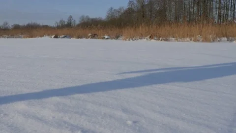 Shadows of two people walk along the shore on a frozen lake 2 Stock Footage 149809629