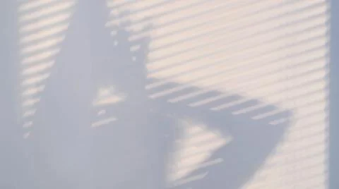 Shadows on the wall from a window closed with blinds and a woman's silhouette Fotos de archivo